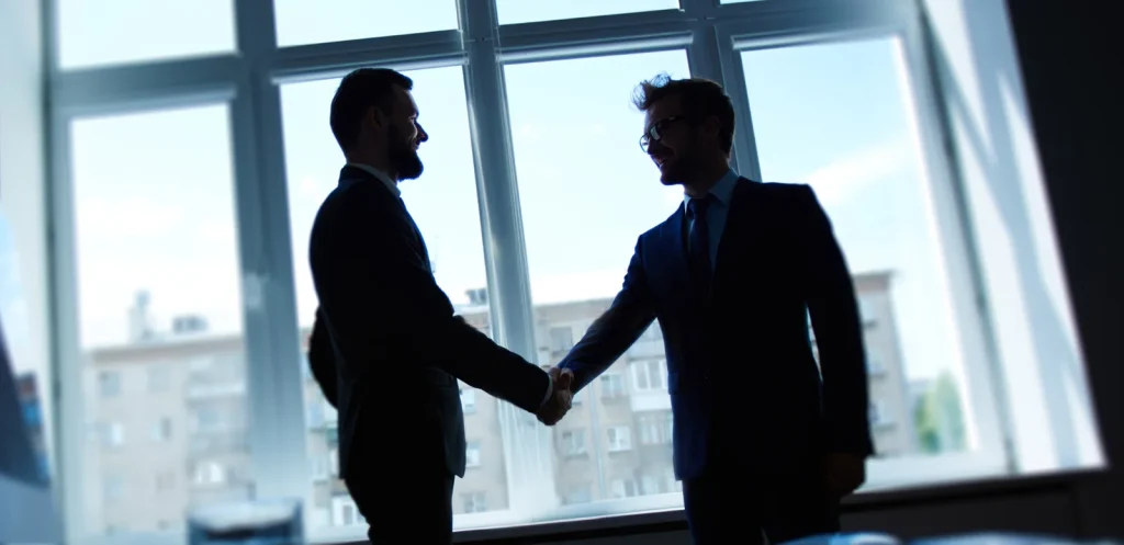 Two people shaking hands in office space